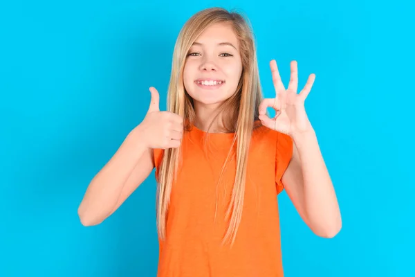 Küçük Kız Mavi Arka Planda Turuncu Tişört Giyiyor Gülümsüyor Mutlu — Stok fotoğraf