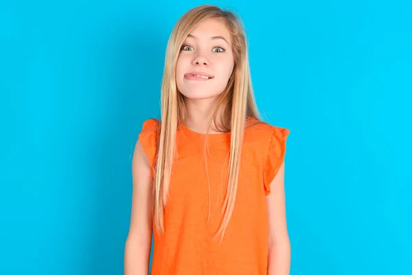 Lustiges Kleines Mädchen Orangefarbenem Shirt Vor Blauem Hintergrund Macht Grimasse — Stockfoto