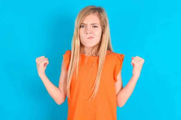 Dráždivá Holčička Oranžovém Tričku Modrém Pozadí Vzteky Udusí Zvedne Zaťaté — Stock fotografie