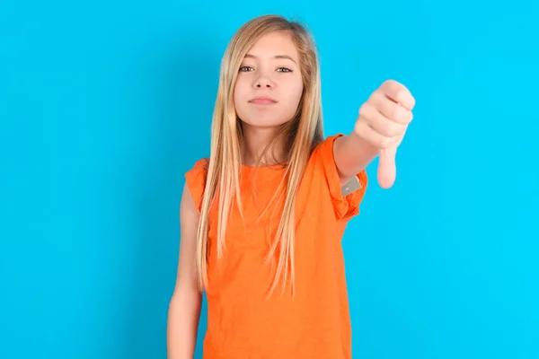 Holčička Oranžovém Tričku Modrém Pozadí Vypadala Nešťastně Rozzlobeně Ukazovala Odmítnutí — Stock fotografie