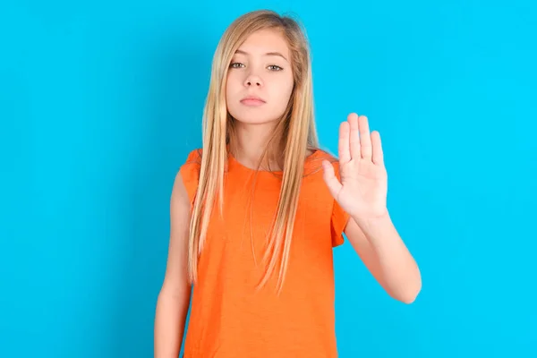 Mała Dziewczynka Nosi Pomarańczowy Shirt Niebieskim Tle Pokazuje Znak Stopu — Zdjęcie stockowe
