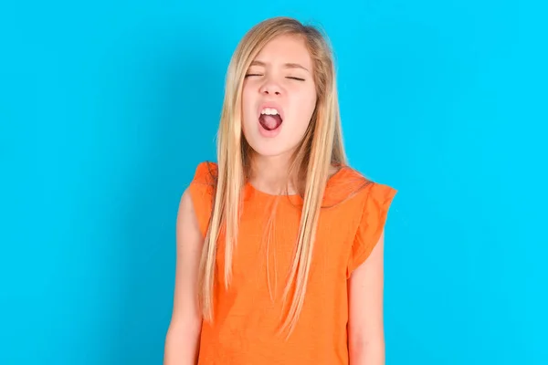 Niña Pequeña Con Camiseta Naranja Sobre Fondo Azul Bosteza Con —  Fotos de Stock