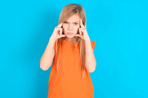 Serieuze Geconcentreerde Kleine Meisje Dragen Oranje Shirt Blauwe Achtergrond Houdt — Stockfoto