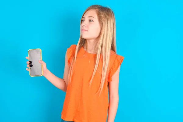 Menina Criança Vestindo Camiseta Laranja Sobre Fundo Azul Detém Novo — Fotografia de Stock