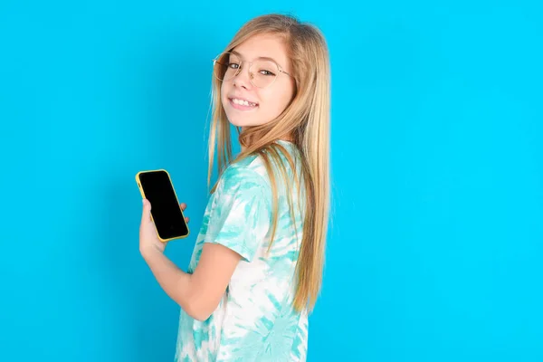 用智能手机微笑拍摄的 穿着蓝色背景的时髦T恤的高加索小女孩的后视镜照片 — 图库照片