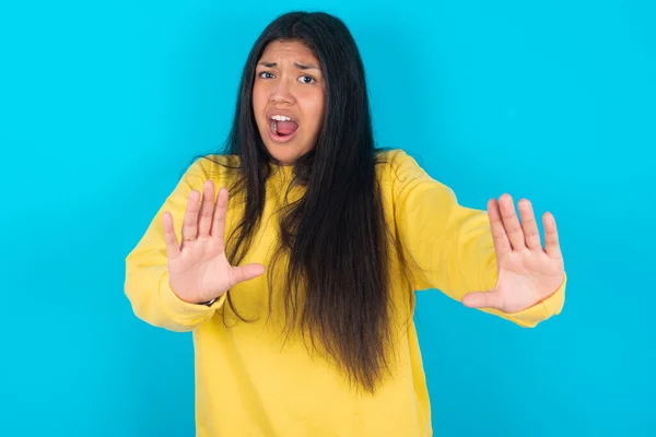 Dissatisfied Latin Woman Wearing Yellow Sweatshirt Blue Background Frowns Face — Stock Photo, Image