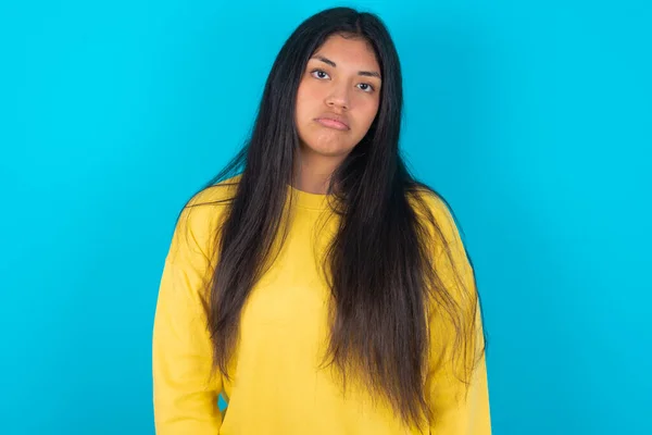Gloomy Bored Latin Woman Wearing Yellow Sweatshirt Blue Background Frowns — Stock Photo, Image