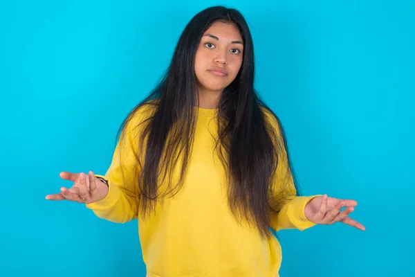 Latin Woman Wearing Yellow Sweatshirt Blue Background Looks Uncertain Shrugs — Stock Photo, Image