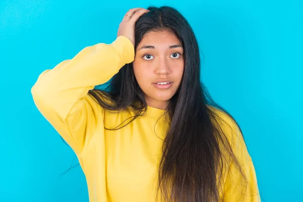 Portrait Confused Latin Woman Wearing Yellow Sweatshirt Blue Background Holding — Stock Photo, Image