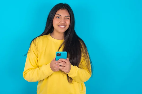 Tevreden Latijnse Vrouw Met Gele Sweater Blauwe Achtergrond Met Behulp — Stockfoto