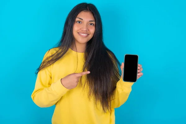 Glimlachende Latijnse Vrouw Met Een Geel Sweatshirt Een Blauwe Achtergrond — Stockfoto