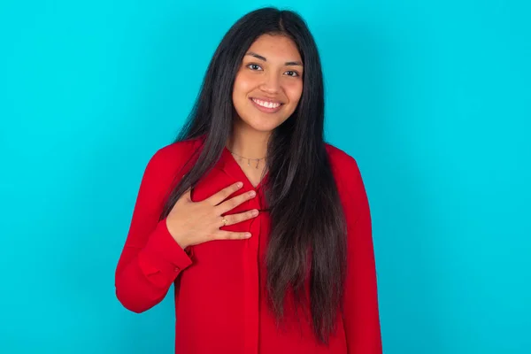 青い背景の笑顔の上に赤いTシャツを着ているラテン系女性は 目が良い感情と驚きを表現することを信じることができません — ストック写真
