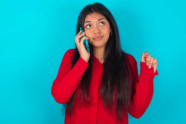 Mulher Latina Vestindo Camiseta Vermelha Sobre Fundo Azul Fala Celular — Fotografia de Stock