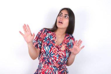 Beyaz duvarın üzerinden renkli elbiseler giyen güzel esmer kadın avuçlarını ileri uzatıyor ve tavandan korkuyla bakıyor kendini görünmez tehlikeden korumaya çalışıyor. Ağzını açıyor..