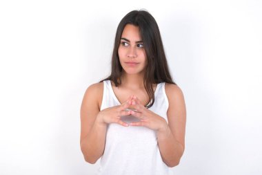 Beyaz bluz giyen esmer kadın parmakları sarkık ve gizemli görünüyor. Kafasında şeytani bir plan var.