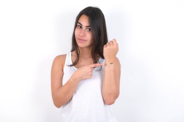 Güzel esmer kadın, beyaz bluz giyip bembeyaz giyinmiş. Aceleyle saati, sabırsızlığı, gecikmeye kızmış ve kızgın olduğunu gösteriyor.