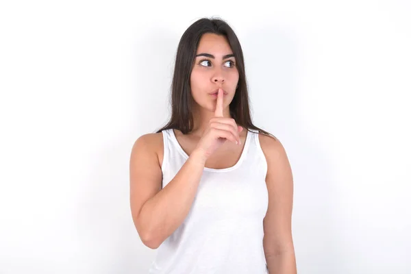 Brunette Woman Wearing White Top White Wall Makes Silence Gesture — Stock Photo, Image