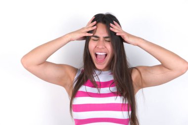 Paniğe kapılmış güzel esmer kadın, beyaz duvarın üzerinde çizgili bir bluz giyiyor, el ele tutuşuyor, umutsuzluk ve hüsran içinde haykırıyor..