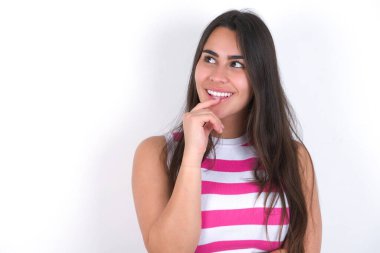 Düşünceli yüzlü bir kız, kameraya bakıyor, elini yüzüne yaklaştırıyor, parmağını ısırıyor, hoş bir şey düşünüyor..