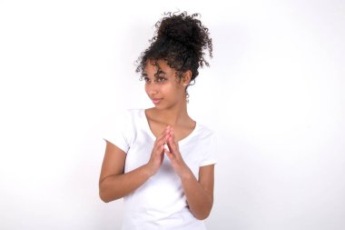 Beyaz arka planda beyaz tişörtlü, afro saçlı, güzel bir kız parmakları dikleşmiş ve gizemli görünüyor. Kafasında şeytani bir plan var.