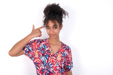 Mutsuz kız dudaklarını kıvırıyor ve intihar jesti yapıyor. Tapınağa eliyle ateş ediyor, kendini öldürmeye çalışıyor. Beyaz duvarda renkli elbiseler giyen güzel melez bir kadın.