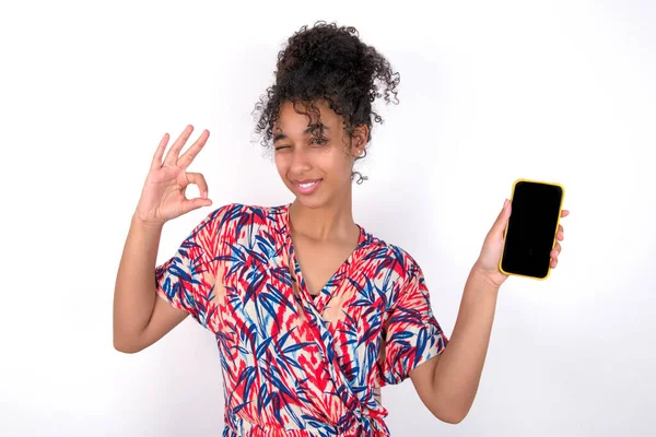 Opgewonden Meisje Toont Smartphone Leeg Scherm Knipperend Oog Doet Teken — Stockfoto