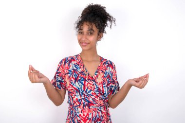 Kız para jesti yapıyor. Beyaz duvarda renkli elbiseler giyen güzel melez bir kadın.