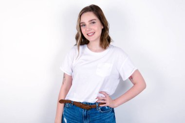 Stüdyodaki neşeli kız el ele tutuşup gülümsüyor. Beyaz arka planda beyaz tişört giyen beyaz bir kadın. 