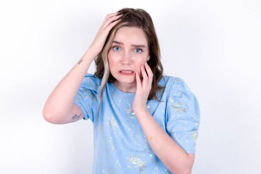 Genç, kasvetli, beyaz arka planda mavi tişört giyen, elleri somurtan, ağlayan, üzgün ve depresyonda olan, iş probleminden şikayet eden, yüzü saklanmış, kasvetli, genç beyaz bir kadın..