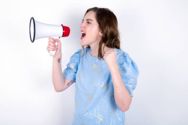 Kız megafonla yüksek sesle iletişim kuruyor, başarıyı ve olumlu konsepti ifade ediyor, pazarlama ya da satış fikri. Beyaz arka planda mavi tişört giyen beyaz bir kadın. 
