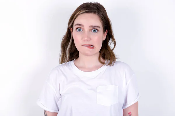 불안하고 무서운 입술을 물고있는 소녀는 인상적인 표현으로 카메라를보고 펜시브 티셔츠를 — 스톡 사진