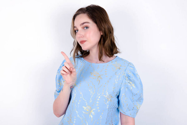 No sign gesture. Closeup portrait unhappy young caucasian woman wearing blue T-shirt over white background raising fore finger up saying no. Negative emotions facial expressions, feelings.