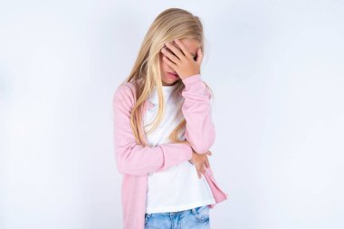 Sarı küçük kız pembe ceketli ve gözlüklü beyaz arka planda elleri olan gözleri örtüyor.