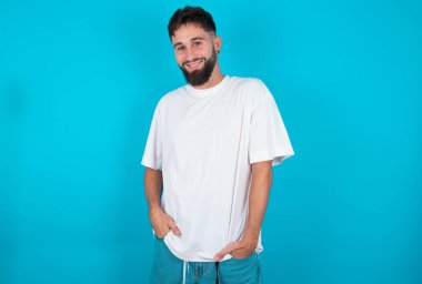 Mavi arka planda beyaz tişört giyen beyaz sakallı beyaz adamın portresi kendine güvenen bir ifadeyle gülümsüyor. Güven ve iş kavramı.