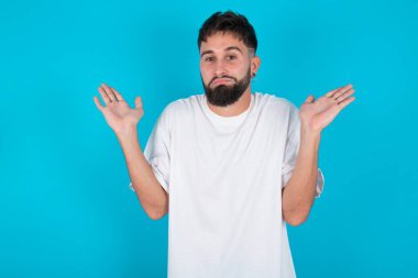 Belki evet ya da hayır. Mavi arka plan üzerine beyaz tişört giyen beyaz sakallı beyaz bir adam şaşkınlık içinde omuz silkiyor, ne istediğine karar vermeye çalışıyor. Tereddüt ve belirsizlik.