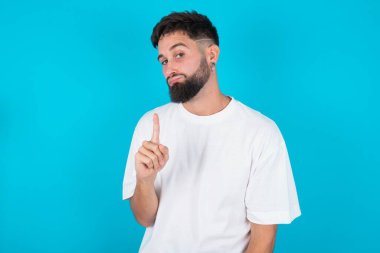 İşaret yok. Mavi arka plan üzerinde beyaz tişört giyen mutsuz, beyaz sakallı beyaz bir adam hayır diyerek parmağını kaldırıyor. Olumsuz duygular, yüz ifadeleri, duygular.