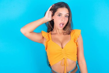 - Aman Tanrım! Komik, şaşkın, güzel esmer kadın. Mavi arka planda turuncu bir atlet giyiyor. Ağzını açıyor..