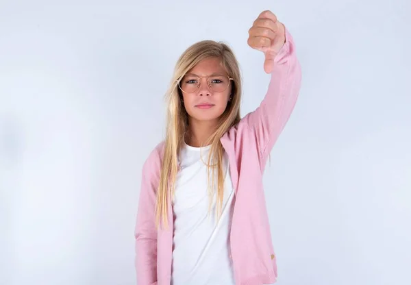 Блондинка Розовой Куртке Очках Белом Фоне Показывает Большой Палец Вниз — стоковое фото