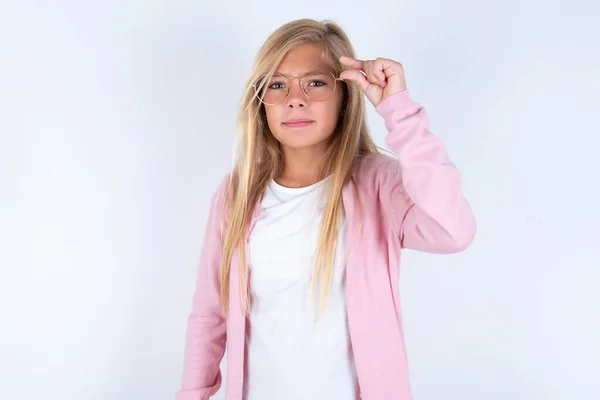 Маленькая Блондинка Розовой Куртке Очках Белом Фоне Делает Маленький Жест — стоковое фото