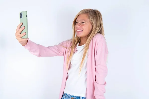 Блондинка Розовой Куртке Очках Белом Фоне Делает Селфи Мобильного Телефона — стоковое фото