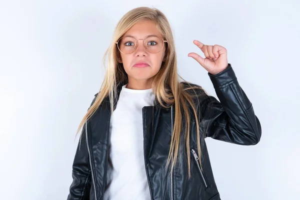 girl purses lip and gestures with hand, shows something very little.