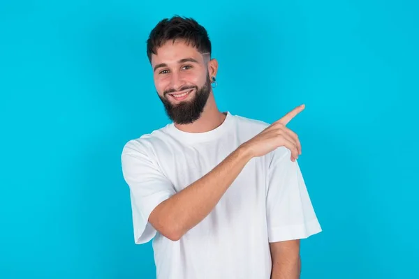 Homem Caucasiano Barbudo Vestindo Camiseta Branca Sobre Fundo Azul Apontando — Fotografia de Stock