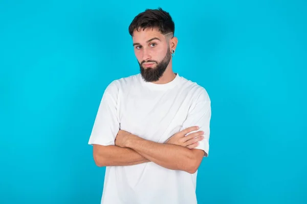 Homem Caucasiano Barbudo Vestindo Camiseta Branca Sobre Fundo Azul Franzindo — Fotografia de Stock