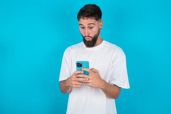 Bearded Caucasian Man Wearing White Shirt Blue Background Looks Bugged — Stock Photo, Image