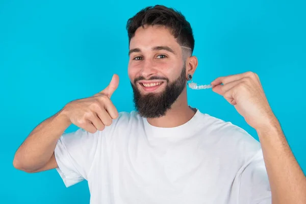 Hombre Caucásico Barbudo Con Camiseta Casual Sobre Fondo Azul Sosteniendo —  Fotos de Stock