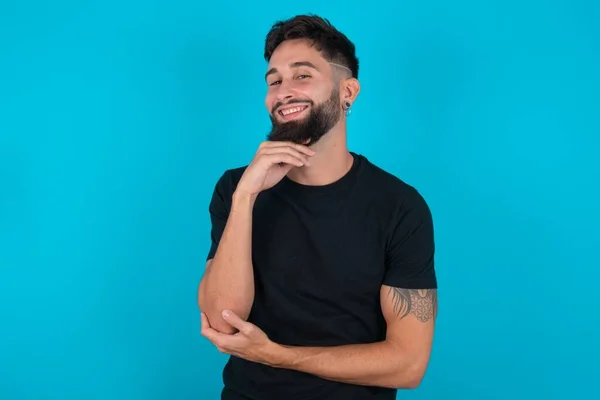 Optimistische Latino Bebaarde Man Met Zwart Shirt Tegen Blauwe Achtergrond — Stockfoto