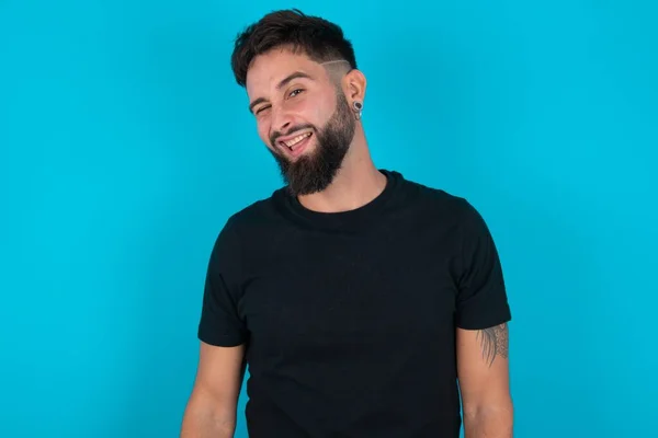 Jonge Spaanse Baardman Met Zwart Shirt Tegen Een Blauwe Achtergrond — Stockfoto