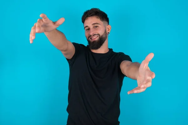 Latino Bebaarde Man Met Zwart Shirt Tegen Een Blauwe Achtergrond — Stockfoto