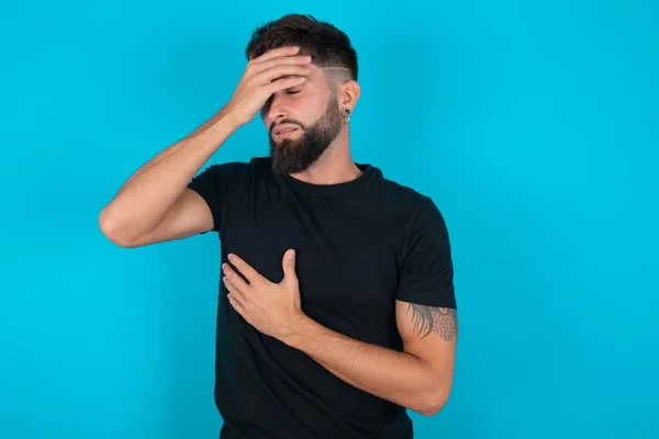 Latino Bebaarde Man Met Zwart Shirt Tegen Een Blauwe Achtergrond — Stockfoto