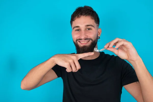 Homem Barbudo Hispânico Vestindo Camiseta Preta Contra Fundo Azul Segurando — Fotografia de Stock